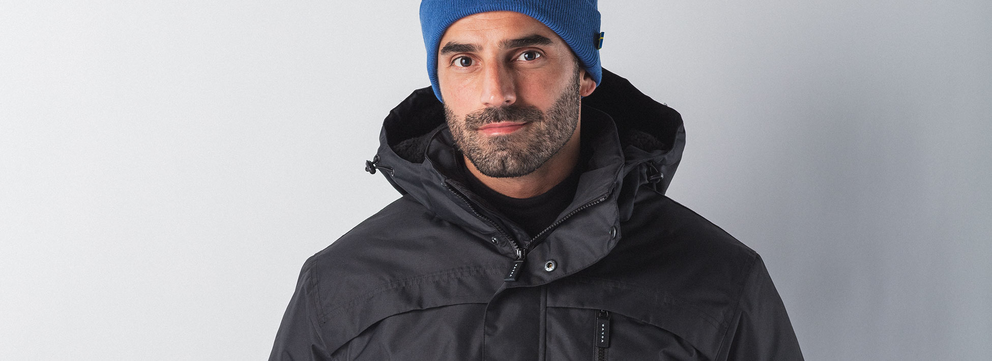 Man wearing black winter jacket and blue beanie from Volvo Merchandise.