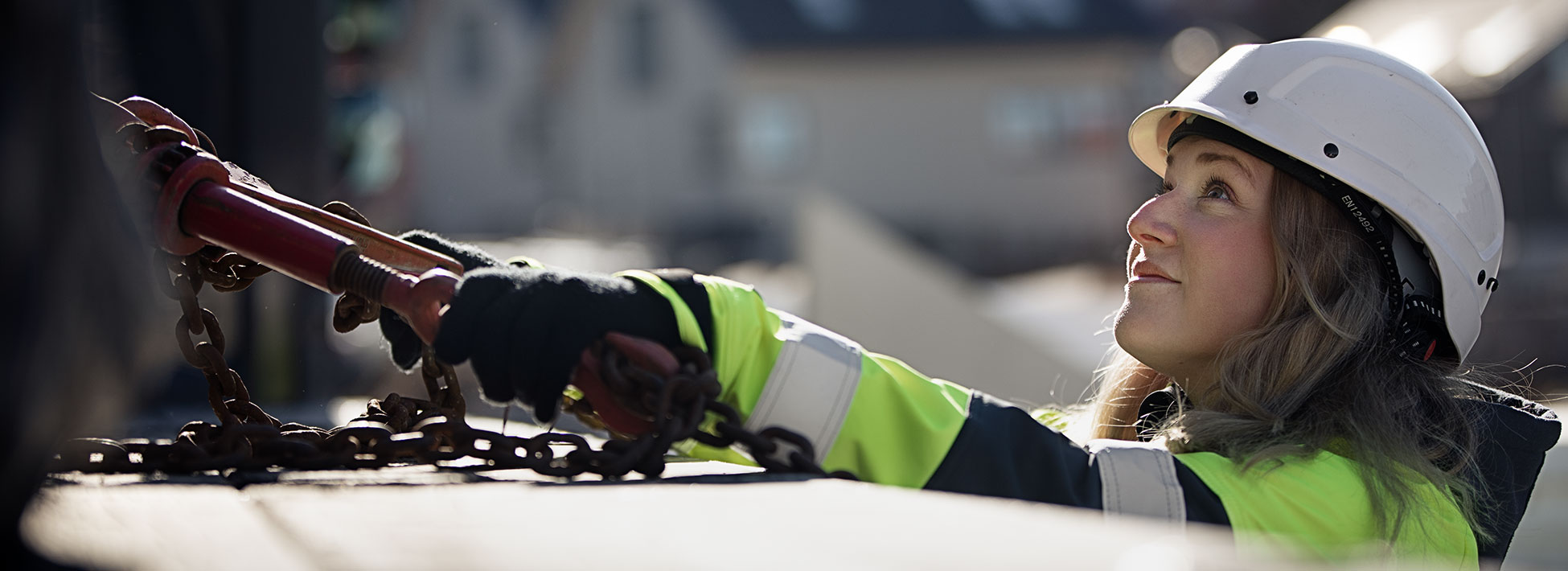 Woman wearing Volvo high-vis workwear and safety helmet on work site.