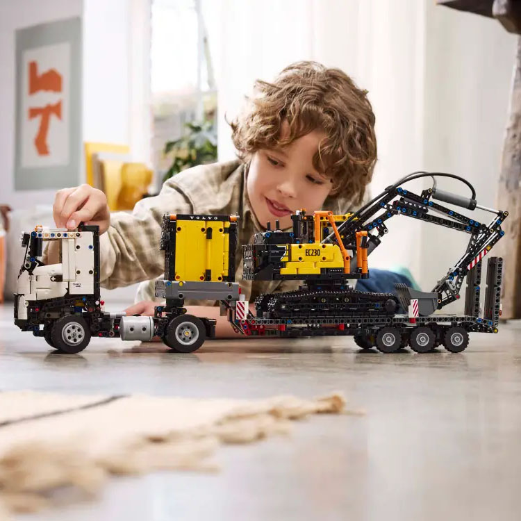 Boy playing and constructing  with Lego Volvo Trucks and Excavator